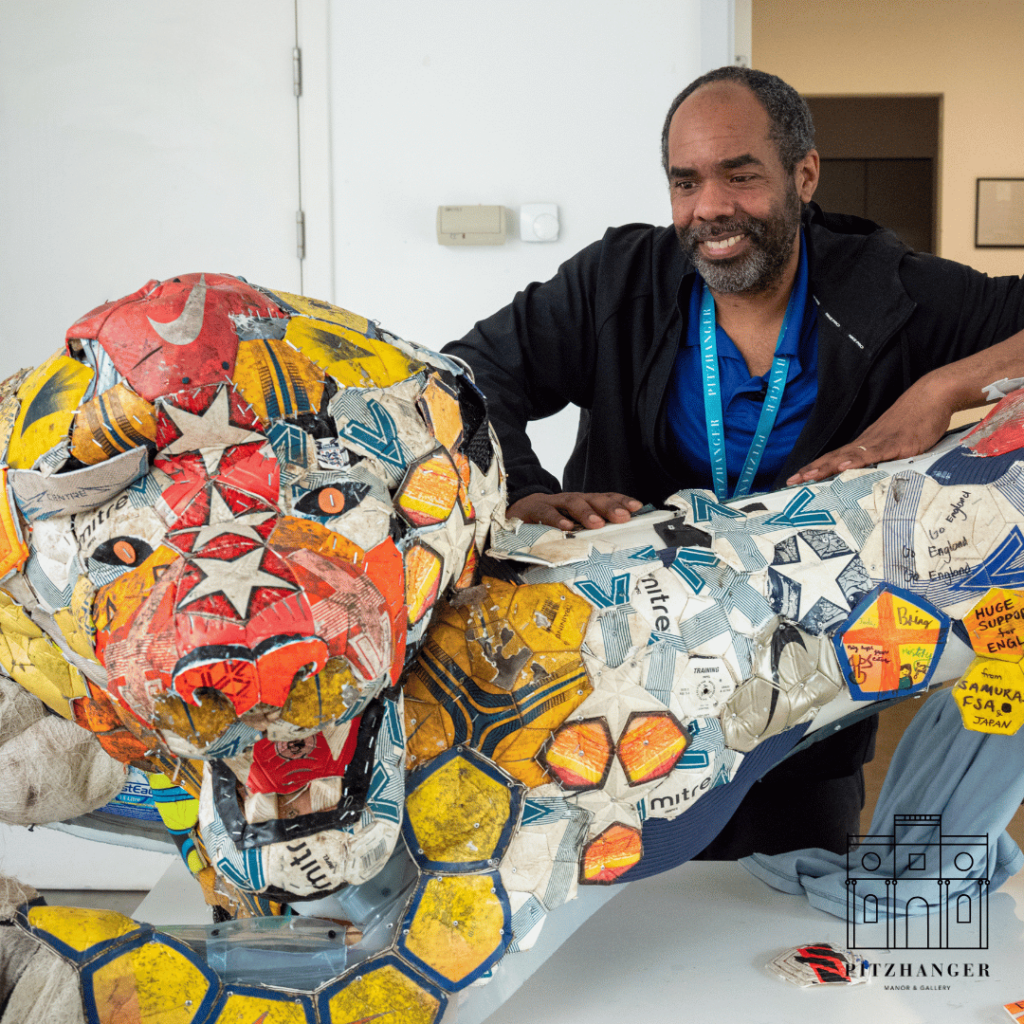 Artist Matt Small smiles beside a completed colorful lion sculpture made collaboratively with local children at Pitzhanger Manor.