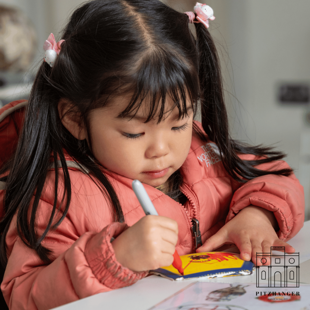 A young girl in pink thoughtfully colors a patch for the recycled lion sculpture at the creative workshop.