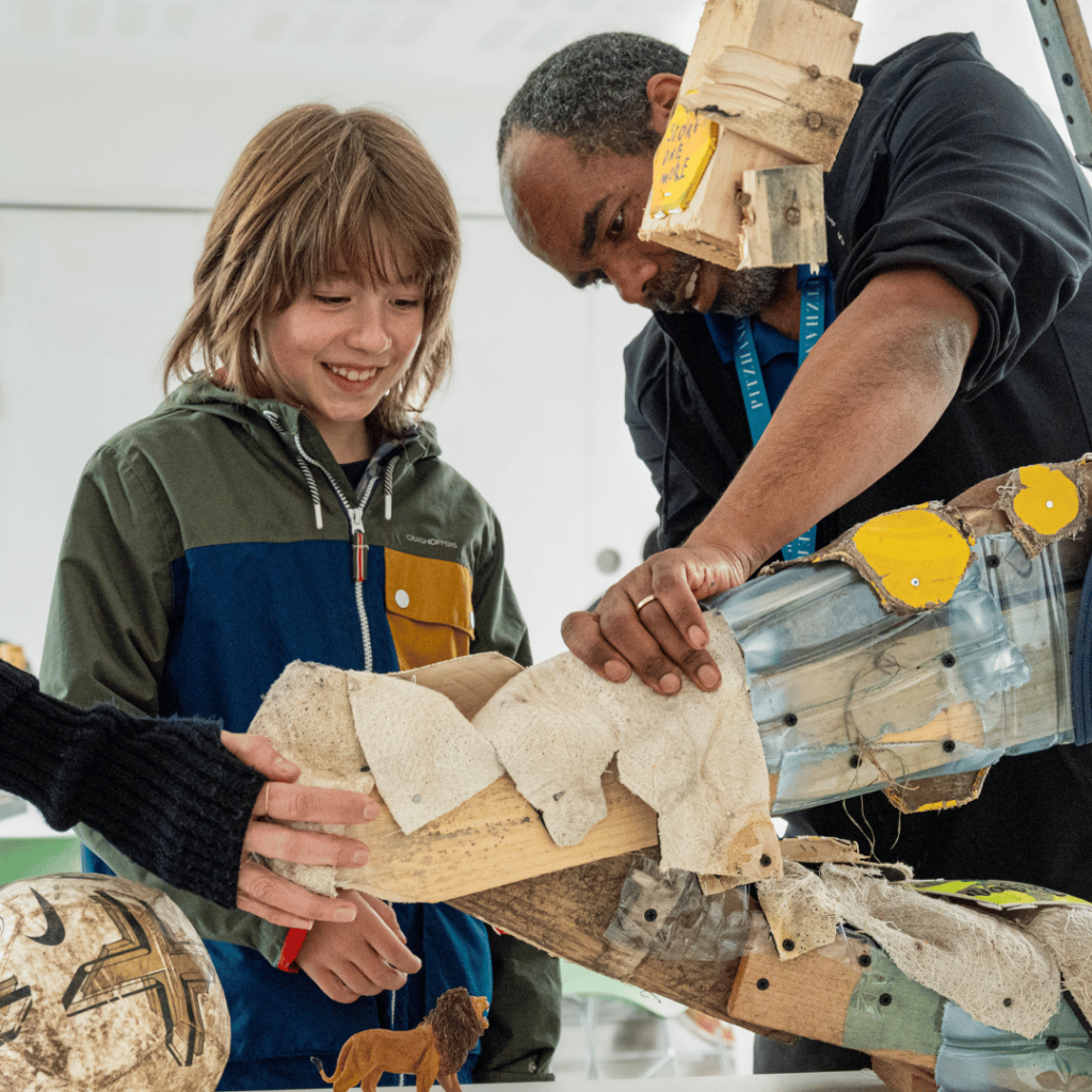 A workshop where a child and instructor collaborate on a creative sculpture, fostering learning and engagement.