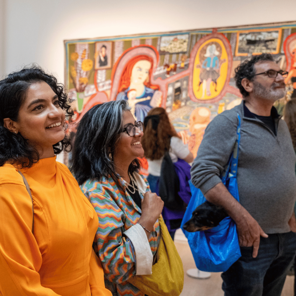 Visitors captivated by vibrant tapestries, reflecting moments of cultural appreciation in a gallery space.